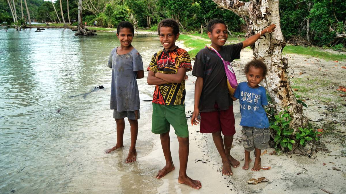 Three boys standing on a beach in Papua New Guinea.